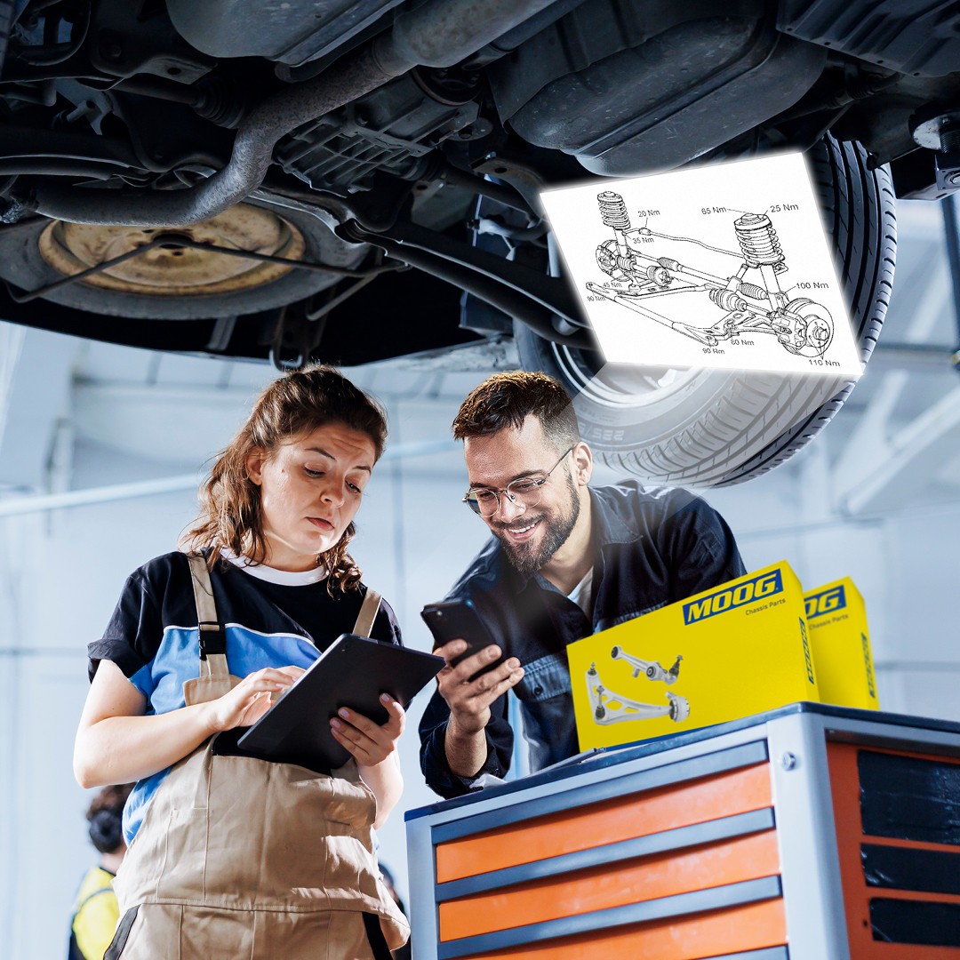 Two installers looking at the MOOG Steering and Suspension technical drawing in a garage
